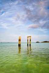 Concrete pillars of an old abandoned jetty on turquoise water beach of an island of Thailand