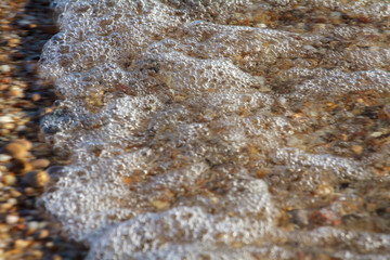 sea pebbles colored granite on the beach background stones. The shore of the beach with sand and pebbles washed by the waves of the sea.