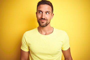 Obraz premium Young handsome man wearing casual yellow t-shirt over yellow isolated background smiling looking to the side and staring away thinking.