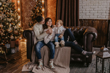 Obraz premium New Year. Christmas. Family. Young parents and their little daughter in Santa hats are spending time together near the Xmas tree at home - Image