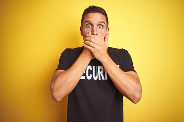Young safeguard man wearing security uniform over yellow isolated background shocked covering mouth...