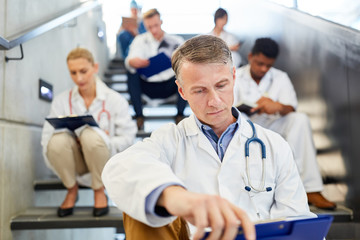 Senior doctor reads in a medical file in the stairwell