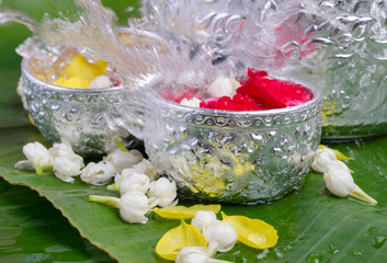 Jasmine and roses in silver bowl on leaves of banana background ,Songkran festival in Thailand