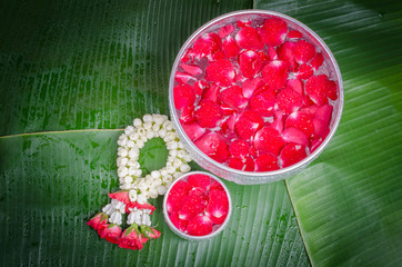 Jasmine and roses in silver bowl on leaves of banana background ,Songkran festival in Thailand
