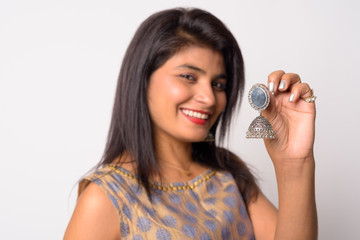 Face of happy young Persian woman holding earring in traditional clothing