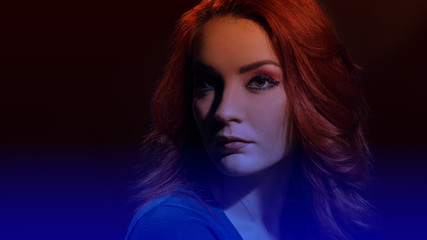 Portrait of beautiful redheaded woman with curly hairstyle and bright makeup, image with soft dark blue gradient