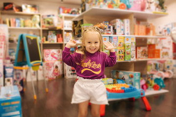 Happy little girl walkning in toy store. Cute girl choose toy. Adorable female in kids mall