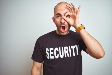 Young safeguard man wearing security uniform over isolated background doing ok gesture shocked with...