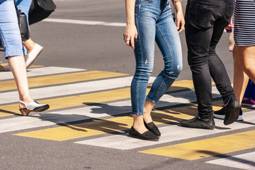 legs of young pedestrians walking on the crosswalk