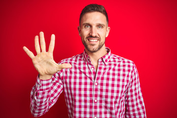 Young handsome man over red isolated background showing and pointing up with fingers number five while smiling confident and happy.