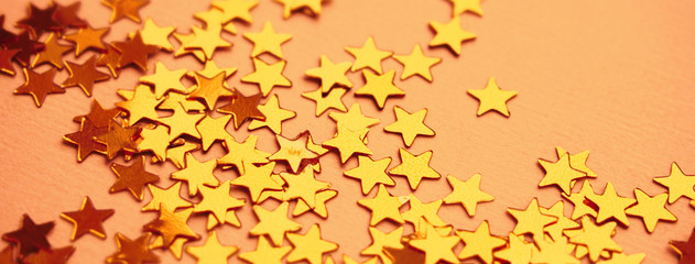 Golden stars glitter on orange paper background