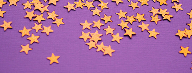 Golden stars glitter on lavender paper background