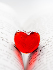 Red transparent glass heart lay in a book