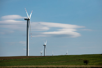 Fototapeta premium Wind turbines on green hills, Group of windmills for electric power production in the green