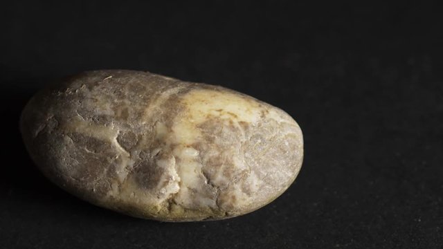 Rock rotating on a black background; isolated on black; close up shot.