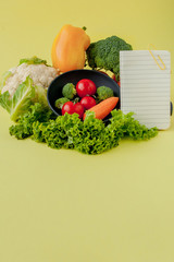 Vegetables and notebook with copy space on yellow background. Bio Healthy food, Organic vegetables on yellow background