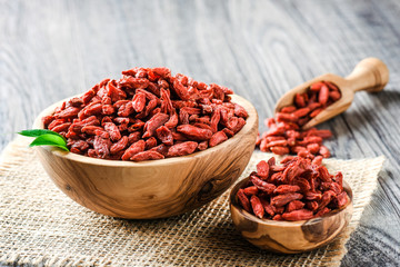 Goji fresh fruits seeds in wooden bowl with scoop ful of goji. Goji on table.