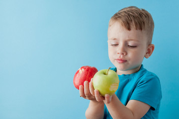 Little Boy Holding an Apples in his hands on blue background, diet and exercise for good health concept