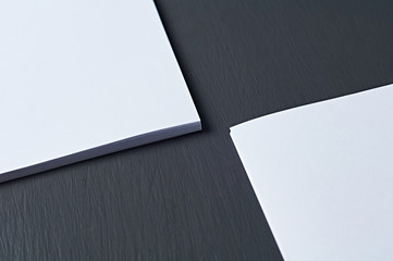 Two corners of stacks of empty white paper sheets lies on dark concrete table on workplace of secretary, director, boss or other worker of company. Space for text