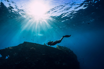 Free diver girl in pink swimwear with fins swimming underwater at wreck ship. Freediving in the...