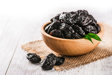 Prunes in wooden bowl on old rustic table. dried plums on table. Heap of prunes on old board.
