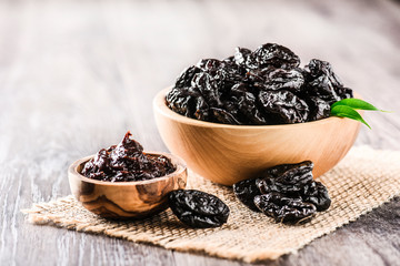 Prunes in wooden bowl on old rustic table. dried plums on table. Heap of prunes on old board.