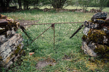 une vieille entrée en pierres devant un pré. Une vieux muret de campagne. 