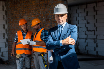 selective focus of businessman standing with crossed arms near constructors