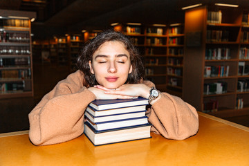 Girl fell asleep at table, hugging stack of books