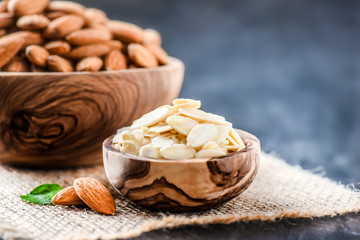 Almonds in bowl in background. Peeled almonds in small wooden olive bowl. Fresh almonds.