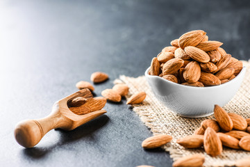 Almonds on dark stone table. Fresh peeled almonds in bowl. Almonds in scoop.