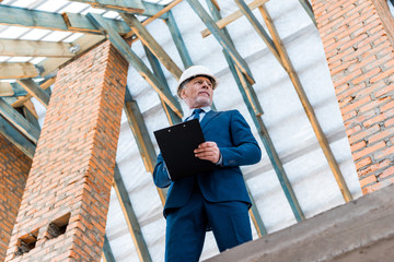 low angle view of businessman in helmet holding clipboard