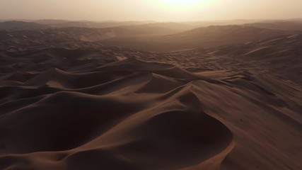 Drone flying over massive sand dunes at sunrise. Aerial bird view of desert landscape. Liwa desert, Abu Dhabi, United Arab Emirates. Epic cinematic background of arabic nature. - Powered by Adobe