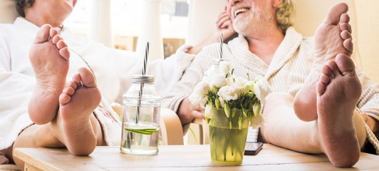 close up of feet of couple of seniors on the tale in a resort hotel or at home with a cocktail or...