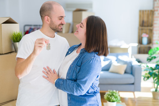 Young couple smiling very happy showing keys of new home, moving and buying new apartmet concept