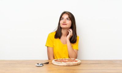 Obraz na płótnie Canvas Caucasian girl with a pizza thinking an idea