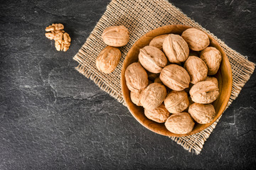 Walnuts top view. Walnut in bowl on black background. Whole walnuts on dark stone table.