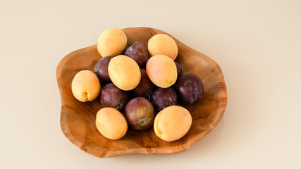 Farm organic plums and yellow apricots. Handmade teak bowl