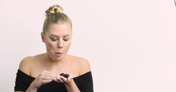 Woman really enjoys blackberries and stuffs them all in her mouth.