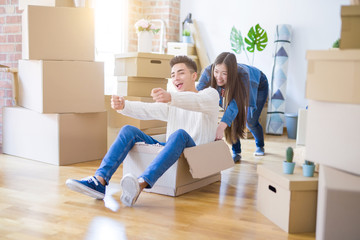 Fototapeta na wymiar Funny asian couple having fun, riding inside cardboard box smiling happy, very excited moving to a new house