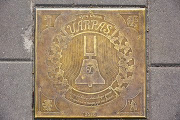 Lithuania, Vilnius - July 2019. Sewer manhole cover. Decorated golden Sewer manhole cover on a cobblestone street. Sewer manhole with golden elements on cobblestone road. Old metal sewer manhole