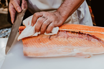 Professional chef preparing a fresh salmon on a cutting board.