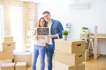 Fototapeta na wymiar Beautiful young couple hugging in love and holding blackboard moving to a new home, smiling happy for new apartment