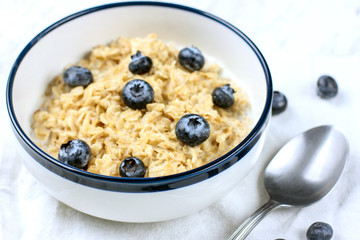 Oatmeal with fresh blueberries. Diet food - oatmeal porridge in a plate with a spoon.