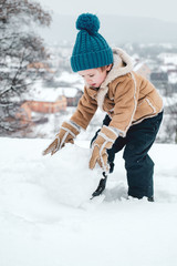 Winter snow and child game. Winter emotion. Joyful little boy child Having Fun in Winter Park. Enjoying nature wintertime. Winter portrait of son in snow Garden.