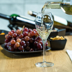 Pouring wine into glass and food background