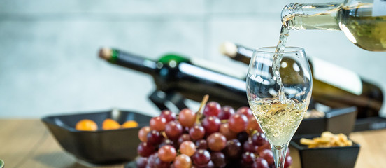Pouring wine into glass and food background