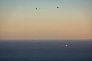 Fototapeta na wymiar Helicopters and ships at dawn over the ocean