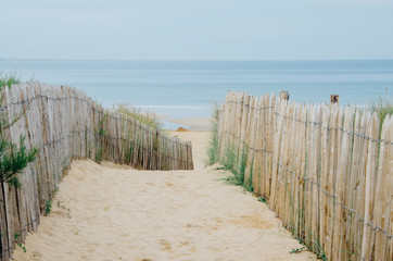 chemin menant à la plage avec une clôture et du sable d'une dune