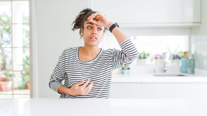 Beautiful african american woman with afro hair wearing casual striped sweater Touching forehead for illness and fever, flu and cold, virus sick